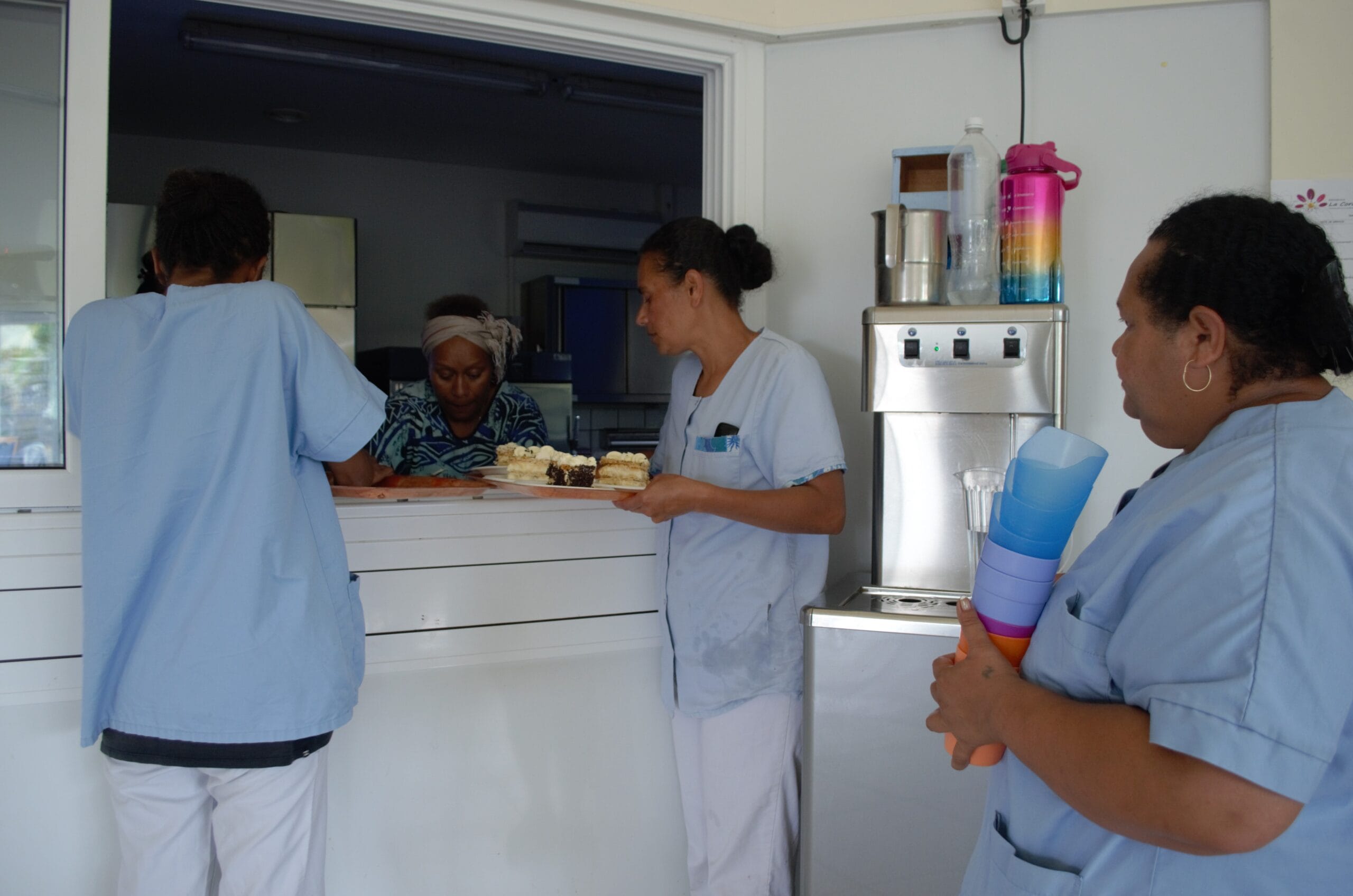 Des membres du personnel de la Résidence La Cordyline en train de préparer et de servir des desserts dans la cuisine de l’établissement.